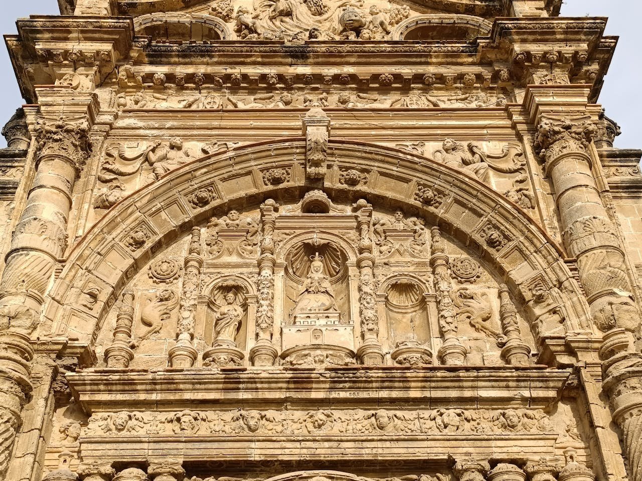 Close-up of an intricately carved stone facade on a historic church in El Puerto de Santa María, Spain.